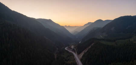 Aerial View of a Scenic Road in the Valley surrounded by Canadian Mountain Landscape during a sunny summer sunset. Taken near Hope, East of Vancouver, BC, Canada.の写真素材