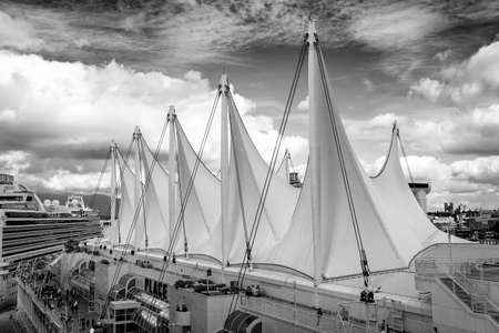 Downtown Vancouver, British Columbia, Canada - September 21, 2019: Black and White Picture of a Famous Landmark in the city, Canada Place, with Cruise Ships docked during a sunny and cloudy day.のeditorial素材
