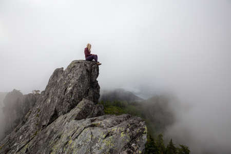 Adventurous Girl on top of a rugged rocky mountain during a cloudy summer morning. Taken on Crown...