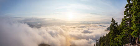 Beautiful Panoramic View of Canadian Mountain Landscape covered in clouds during a vibrant summer sunset. Taken on top of St Mark's Summit, West Vancouver, British Columbia, Canada.の写真素材