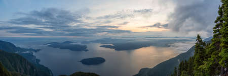 Beautiful Panoramic View of Canadian Mountain Landscape covered in clouds during a vibrant summer sunset. Taken on top of St Marks Summit, West Vancouver, British Columbia, Canada.の写真素材