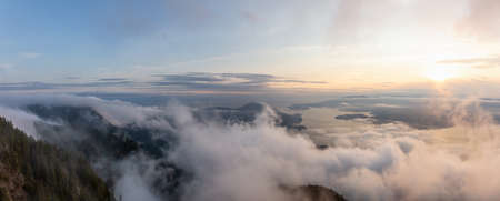 Beautiful Panoramic View of Canadian Mountain Landscape covered in clouds during a vibrant summer sunset. Taken on top of St Marks Summit, West Vancouver, British Columbia, Canada.の写真素材