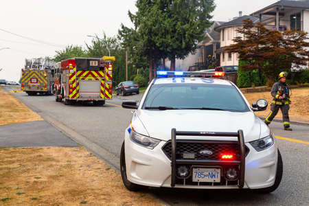 Fraser Heights, Surrey, Greater Vancouver, British Columbia, Canada - August 5, 2017: Police Car Blocking the road white Firefighters are responding to a residential house fire in a neighborhood.のeditorial素材