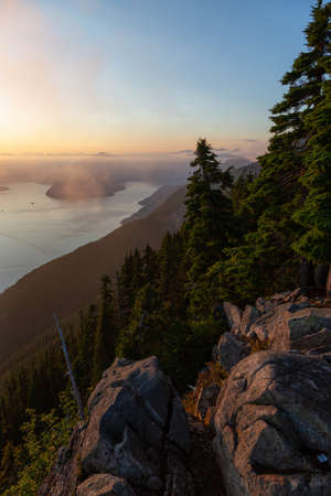 Beautiful View of Canadian Mountain Landscape covered in clouds during a vibrant summer sunset. Taken on top of St Mark's Summit, West Vancouver, British Columbia, Canada.の写真素材