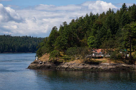 Beautiful View of a Cosy House on the rocky coast during a sunny summer day. Taken on Galiano Island near Vancouver Island, BC, Canada.の写真素材