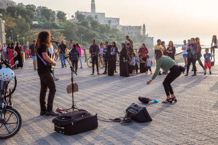 Jaffa, Tel Aviv-Yafo, Israel - April 13, 2019: Man with a guitar is playing and singing in the streets of the Old City of Jaffa during a sunny sunset.のeditorial素材