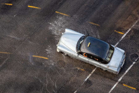 Havana, Cuba - May 29, 2019: Aerial view from above of an Old Car driving on the wet road after a rain pour.のeditorial素材