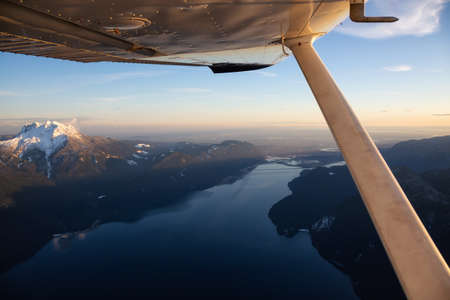 View from the small airplane flying over the Beautiful Canadian Landscape during vibrant sunset. Taken North of Vancouver, British Columbia, Canada.の写真素材