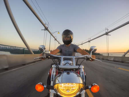 Downtown Vancouver, British Columbia, Canada - June 16, 2018: Man on a motorcycle is riding in a modern city during a sunny summer sunset.のeditorial素材