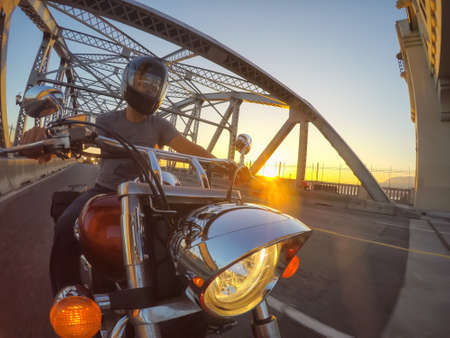 Downtown Vancouver, British Columbia, Canada - June 16, 2018: Man on a motorcycle is riding in a modern city during a sunny summer sunset.のeditorial素材
