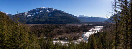 Beautiful panoramic view of a river flowing in a valley surrounded by mountains during a sunny day. Taken near Squamish, North of Vancouver, BC, Canada.の写真素材