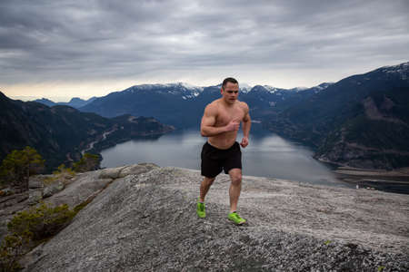 Fit and Muscular Young Man is Running up the Mountain during a cloudy day. Taken on Chief Mountain...