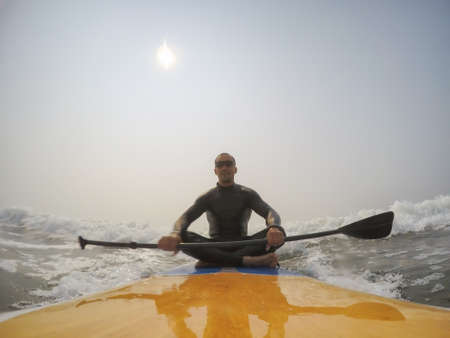 Man paddle surfer is riding a wave in the Pacific Ocean. Taken in Tofino, Vancouver Island, British Columbia, Canada.の写真素材