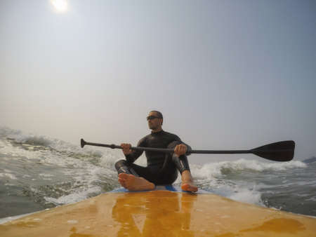 Man paddle surfer is riding a wave in the Pacific Ocean. Taken in Tofino, Vancouver Island, British...