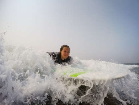 Female beginner surfer is learning how to surf in the Pacific Ocean. Taken in Tofino, Vancouver...