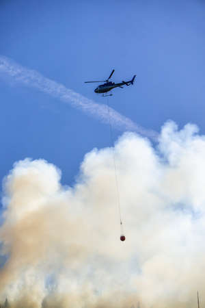Helicopter fighting BC forest fires during a hot sunny summer day. Taken near Port Alice, Northern Vancouver Island, British Columbia, Canada.の写真素材