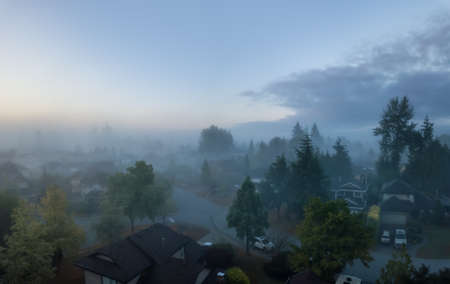 Aerial view of a residential neighborhood covered in a layer of fog during a vibrant sunrise. Taken in Greater Vancouver, BC, Canada.の写真素材