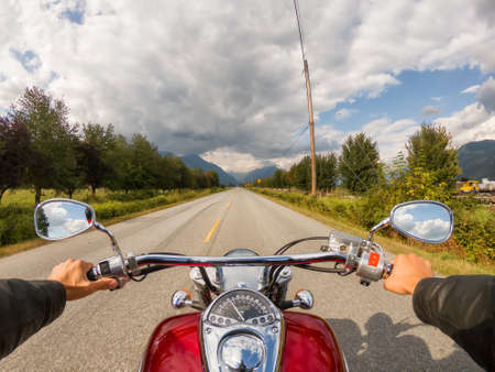 Riding on a motorcycle on a beautiful scenic road surrounded by the Canadian Mountains. Taken in Pitt Meadows, Greater Vancouver, BC, Canada.の写真素材