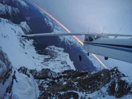 Aerial view of a small airplane flying over the Canadian Mountain Landscape during a gloomy cloudy sunset. Taken near Squamish, North of Vancouver, British Columbia, Canada.の写真素材
