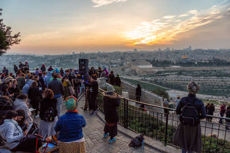 Jerusalem, Israel - April 4, 2019: Crowd of poeple are gathered to celebrate a religious ceremony overlooking the Old City, Dome of the Rock and Tomb of the Prophets during a beautiful sunset.のeditorial素材