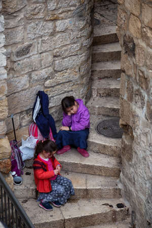 Jerusalem, Israel - April 2, 2019: Aerial view of couple bored children sitting on the stairs in the Old City.のeditorial素材