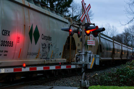 Fort Langley, Greater Vancouver, BC, Canada - December 26, 2018: Train passes the Railroad Crossing during a cloudy winter sunset.のeditorial素材