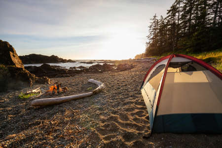 Camp fire on the beach during a vibrant summer sunset. Taken in Northern Vancouver Island Ocean Coast, BC, Canada.の写真素材