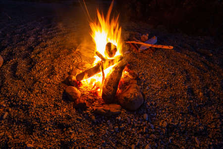 Camp fire on the beach during a vibrant summer sunset. Taken in Northern Vancouver Island Ocean...