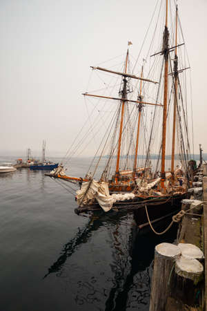 Port Hardy, Vancouver Island, BC, Canada - August 20, 2018: Wooden sailboat parked at a marina during a foggy summer day.のeditorial素材