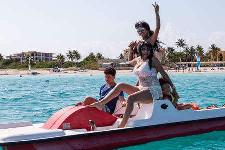 Varadero, Cuba - May 11, 2019: Cuban Family are having fun on a pedal board in the ocean during a...