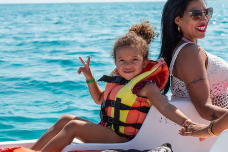 Varadero, Cuba - May 11, 2019: Cuban Family are having fun on a pedal board in the ocean during a...