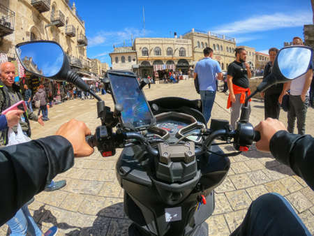 Jerusalem, Israel - April 16, 2019: Riding a scooter in the busy urban streets during a cloudy and...