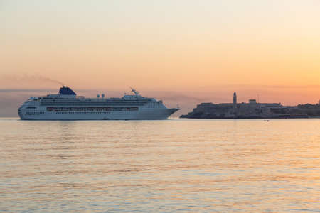 Beautiful view of a Big Cruise Ship arriving to the Old Havana City, Capital of Cuba, during a colorful cloudy sunrise.の写真素材