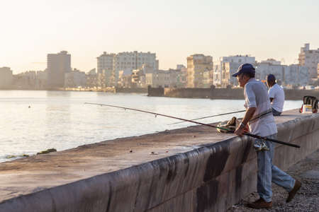 Havana, Cuba - May 14, 2019: Unhappy Cuban people are fishing in the ocean early morning during a sunny sunrise, taken during the Shortage of Food Crisis.のeditorial素材