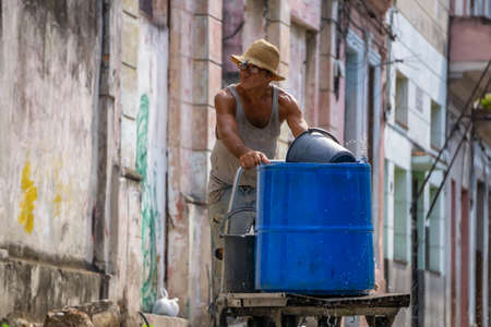 Havana, Cuba - May 17, 2019: Old man pushing a container full of water in the streets of Old Havana City during a hot sunny day.のeditorial素材