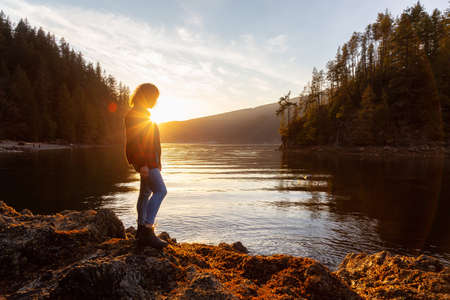 Adventurous Girl Hiking in the Canadian Landscape during a vibrant winter sunset. Hike on Jug Island Trail in Belcarra, Vancouver, British Columbia, Canada. Concept: Freedom, Explore, Healthの写真素材