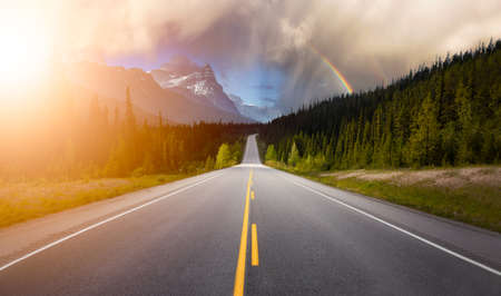 Scenic road in the Canadian Rockies during a vibrant sunny summer day with Rainbow. Rainy Sky Composite. Taken in Icefields Parkway, Banff National Park, Alberta, Canada.の写真素材