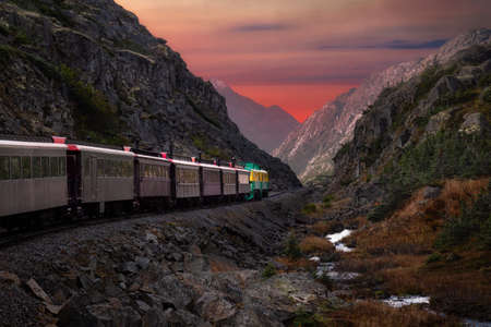 Old Historic Railroad Train is going over White Pass. Moody Colorful Sky Composite. Skagway, Alaska, United Statesの写真素材