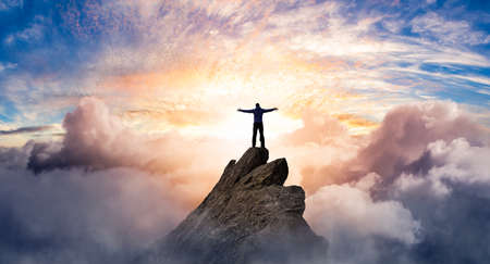Fantasy Adventure Composite with a Man on top of a Mountain Cliff with Dramatic Cloudscape in...