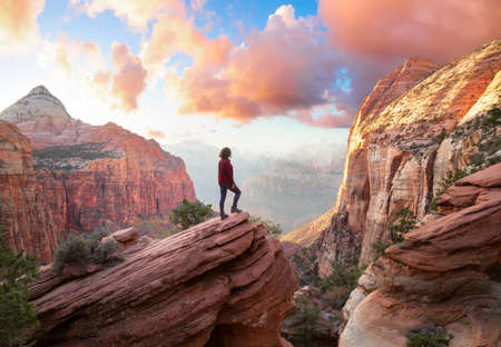 Adventurous Woman at the edge of a cliff is looking at a beautiful landscape view in the Canyon...