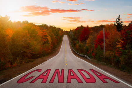Canada Sign on a Scenic Road in the nature with Vibrant Fall Color Trees. Sunset or Sunrise Sky Composite. Road in Nova Scotia.の写真素材