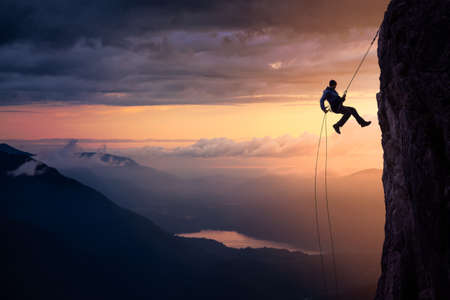 Epic Adventurous Extreme Sport Composite of Rock Climbing Man Rappelling from a Cliff. Mountain Landscape Background from British Columbia, Canada. Concept: Explore, Hike, Adventure, Lifestyleの素材 [FY310149978404]