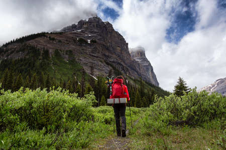 Female Backpacker Hiking in Canadian Rockies during a cloudy day. Taken near Banff, boarder of...