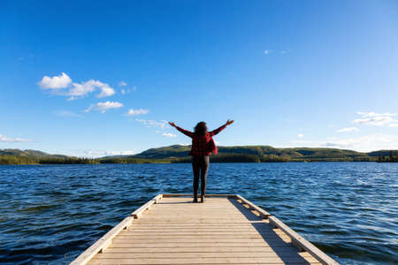 Adventurous Girl on a Wooden Quay at Twin Lakes Campground during a sunny summer day. North of Whitehorse, Yukon, Canada. Concept: travel, adventure, freedomの写真素材