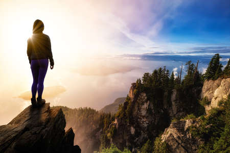 Girl Hiker on top of a Rocky Mountain Cliff overlooking the beautiful Canadian Nature Landscape...
