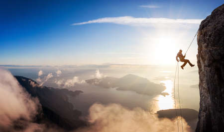 Epic Adventurous Extreme Sport Composite of Rock Climbing Man Rappelling from a Cliff. Mountain Landscape Background from British Columbia, Canada. Concept: Explore, Hike, Adventure, Lifestyleの写真素材
