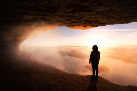 Girl Hiker on top of a Rocky Mountain Cliff overlooking the beautiful Nature Landscape during a colorful sunny sunset. Adventure Dreamscape Composite. Background from British Columbia, Canada.の写真素材