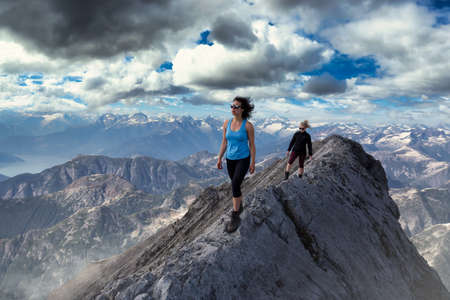 Epic Extreme Hikers on the Rocky Ridge on top of a Mountain. Adventure Compoosite. Aerial Background from British Columbia, Canada.の写真素材