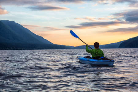 Beautiful View of Person Kayaking on Scenic Lake at Sunset surrounded by Mountains in Canadian Nature. Taken in Golden Ears Provincial Park, near Vancouver, British Columbia, Canada.の写真素材