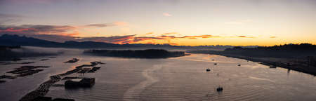 Aerial Panoramic View of Fraser River. Dramatic Colorful Sunrise Sky. Taken over Port Mann Bridge in Surrey, Vancouver, British Columbia, Canada.の写真素材